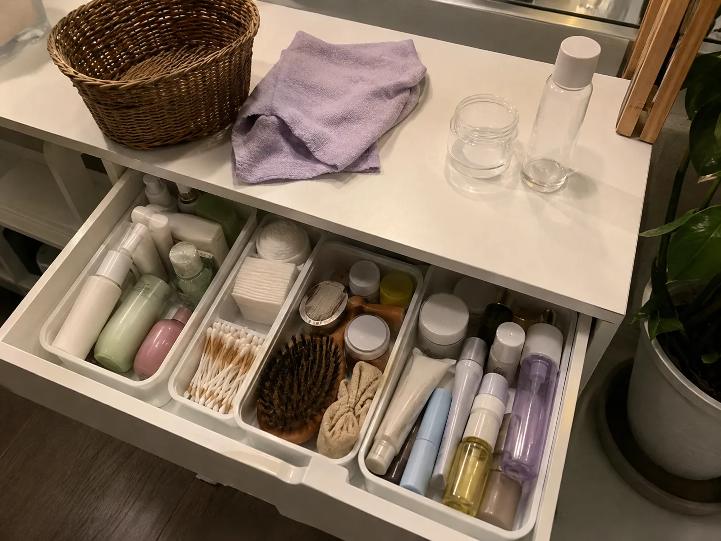 Organised bathroom drawer with everyday toiletries, skincare products, cotton pads, hairbrush and small storage trays.
